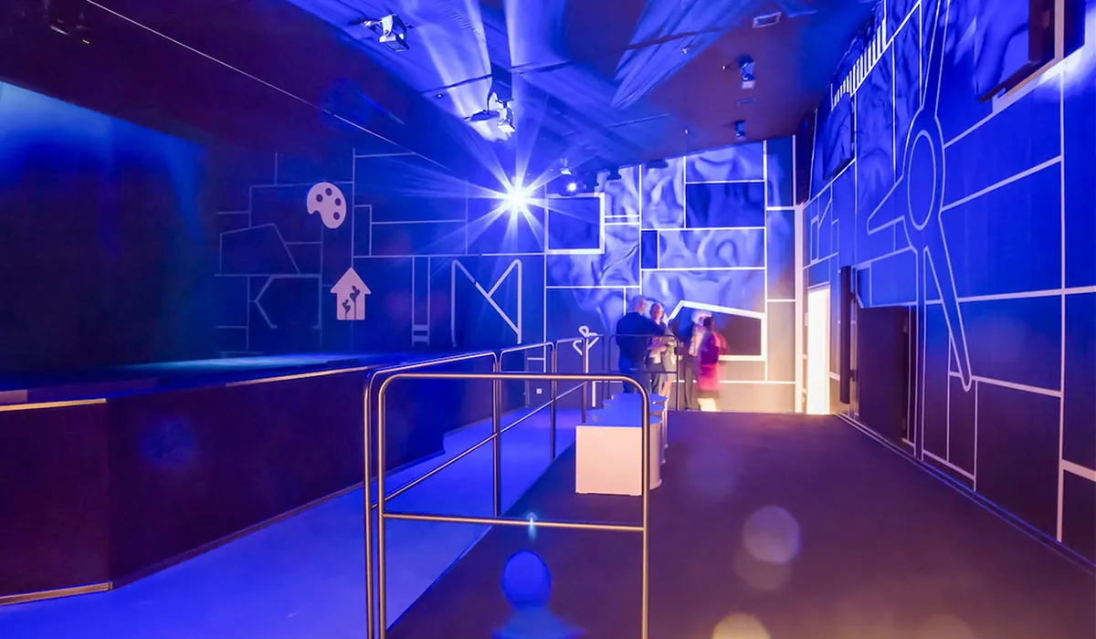 A corridor bathed in deep blue and violet light, white linework of turbines and icons on the walls