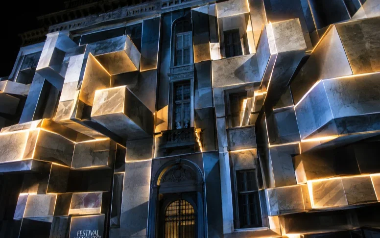 A projection-mapped facade mid-effect, geometry appearing to extrude from the building.