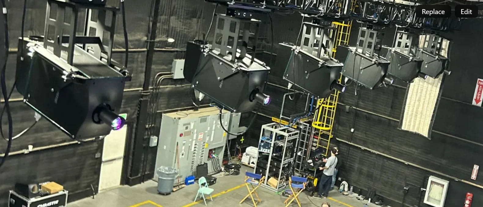 A large-venue projector on a rigging frame, its beam cutting through haze.
