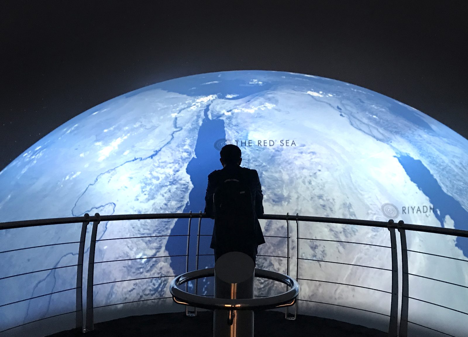 A planner standing before a region-scale projected globe